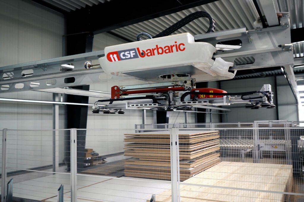 Ein automatisiertes Lagersystem mit der Aufschrift "CSF barbaric", das Holzplatten in einer Lagerhalle bewegt.